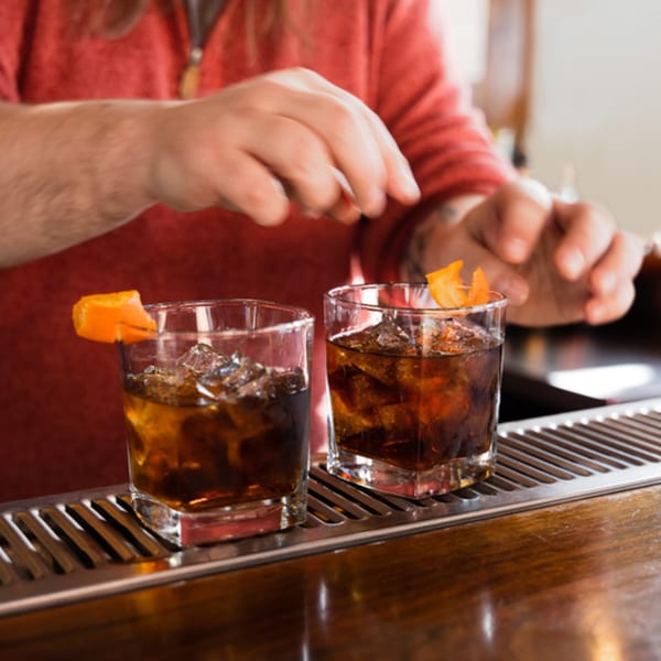 Bartender garnishing two Old Fashioned cocktails with orange peels at 412 Public House.