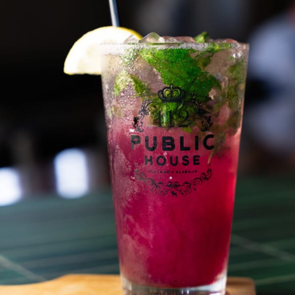A vibrant red cocktail with mint, ice, and a lemon slice, branded with "412 Public House".